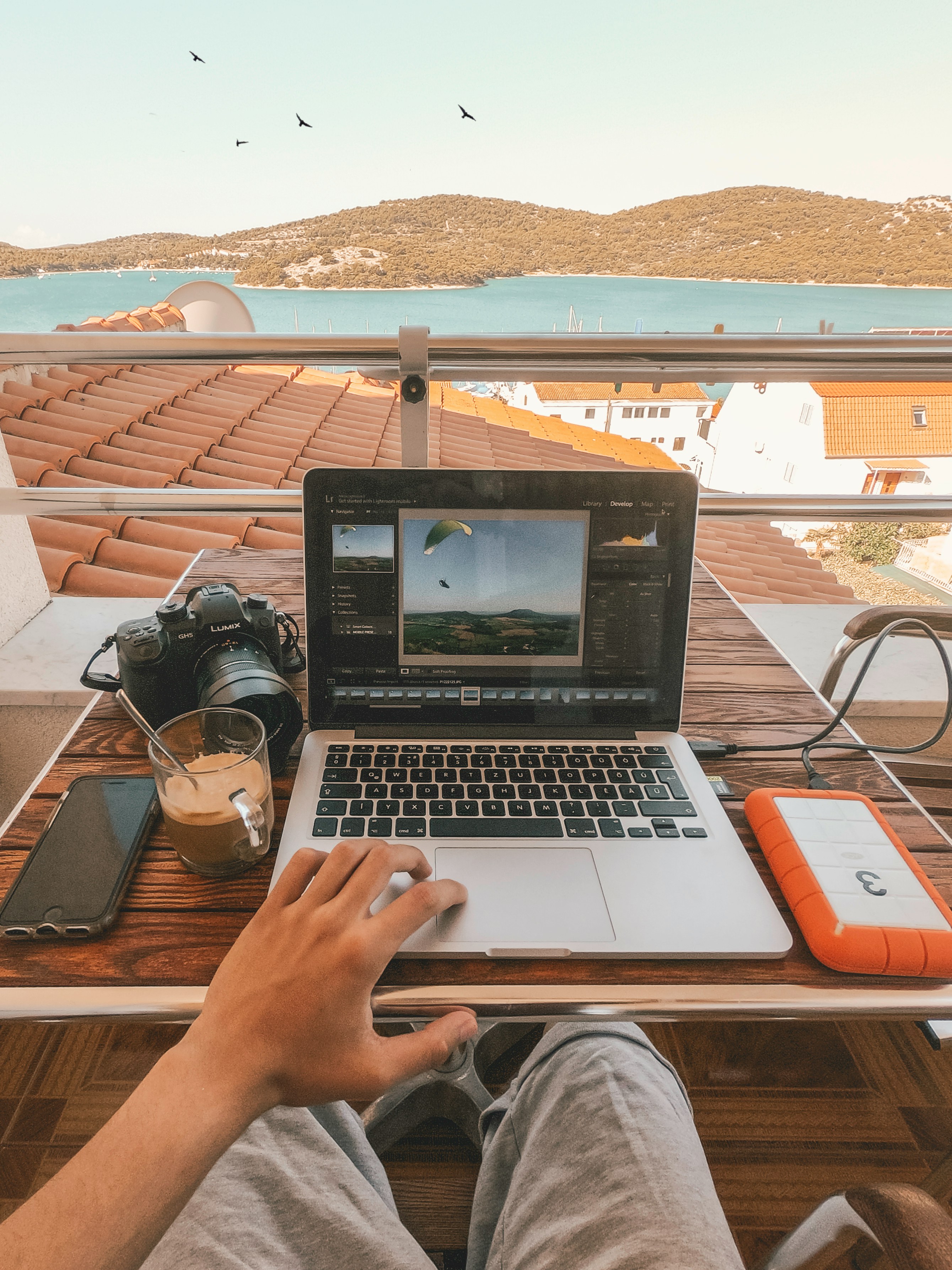 Laptop and camera on a balcony table above the water