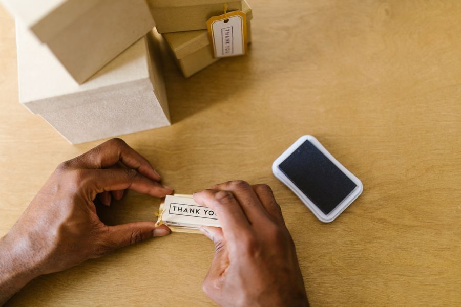 Business owner tying a thank-you tag to a packed customer order