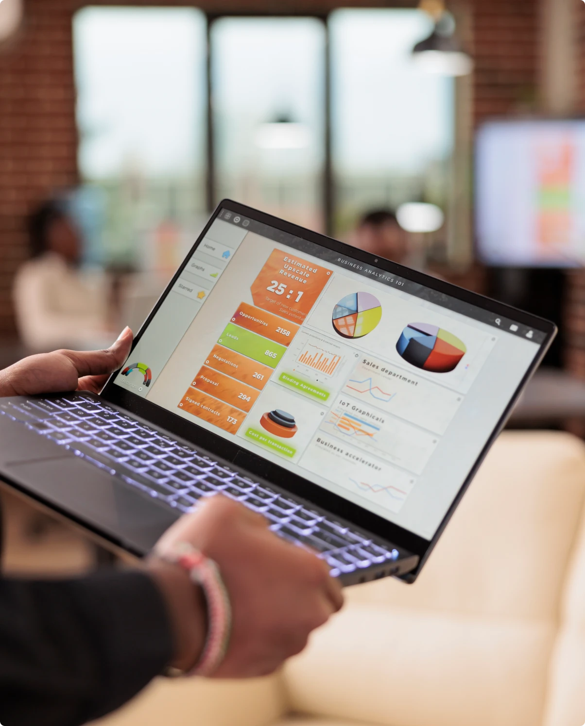Hands holding an open laptop that shows a business analytics dashboard