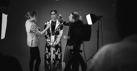 Stylists preparing a model on a lit studio set