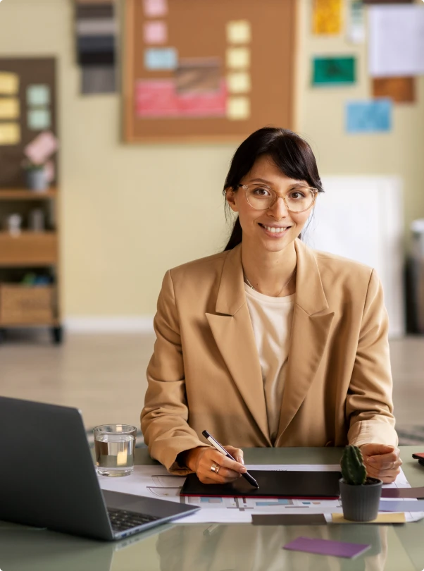 Smiling professional seated at a desk with a laptop