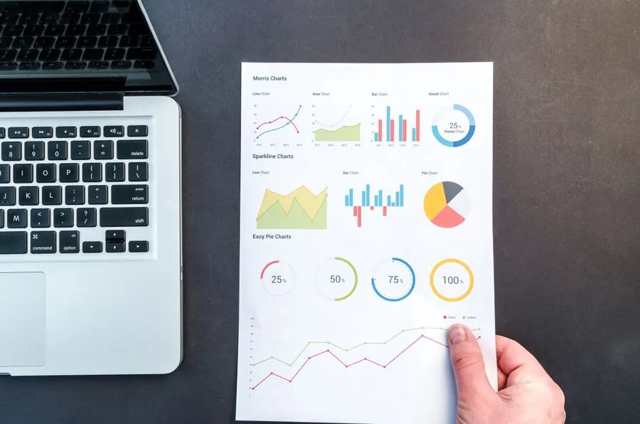Printed chart report held beside a laptop