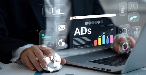 Businessperson at a laptop surrounded by floating ad graphics and charts