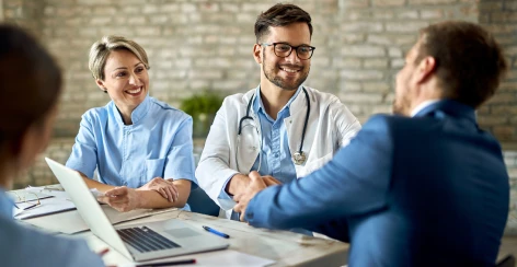 Doctor and nurse greeting a patient at a consultation desk