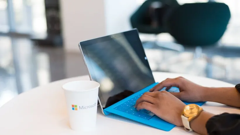 Typing on a Surface laptop beside a Microsoft coffee cup