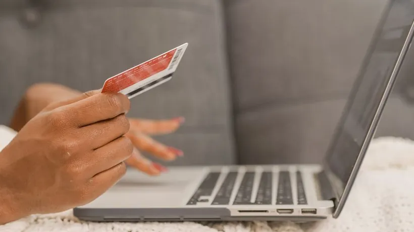 Shopper holding a credit card while buying on a laptop