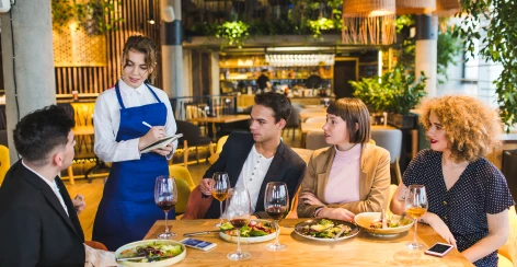 Server taking an order from diners at a restaurant table