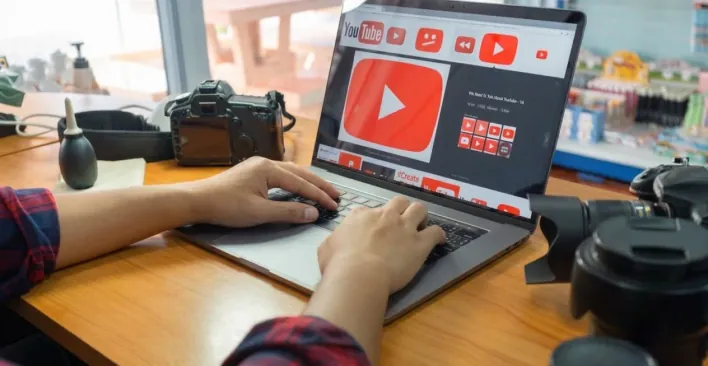 A laptop playing a YouTube video beside a camera