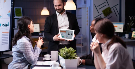 Presenter showing a chart on a tablet to colleagues in a meeting
